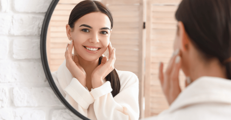 Woman smiling looking at the mirror displaying the importance of presentability in improving self-esteem.