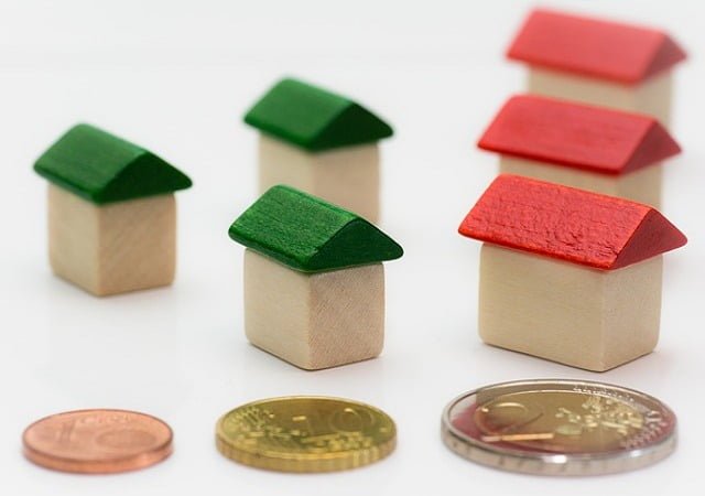 Miniature houses with green and red roofs and scattered coins, representing the need for the best debt repayment strategy in various financial situations.