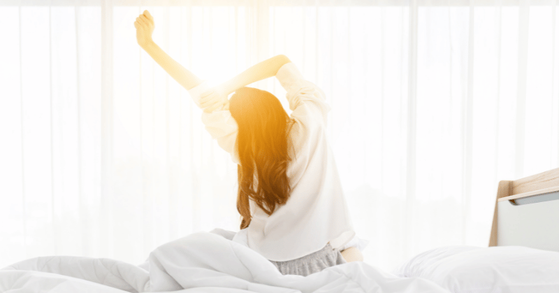 A woman stretching her arms on the bed, symbolising 30 day challenge ideas for morning routines