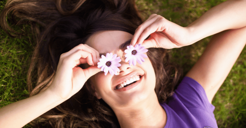 A smiling girl with flowers instead of sunglasses demonstrating happiness when finding obsession