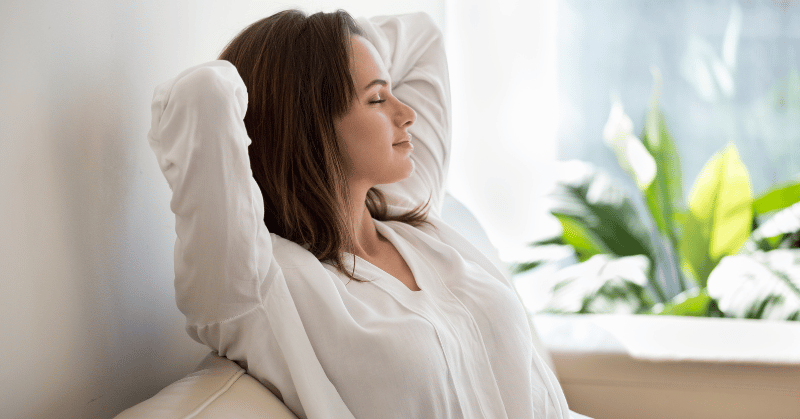 Woman resting looking relaxed and peaceful symbolising the importance of rest for productivity.