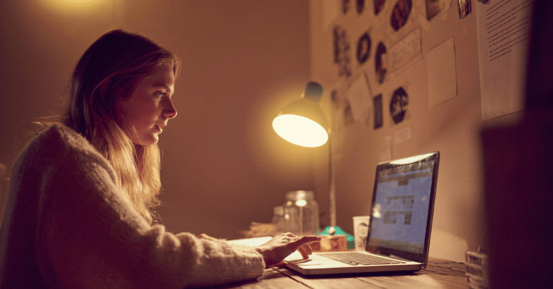 Woman using her laptop in her bedroom at night demonstrating the concept of wasting time