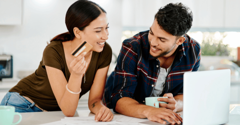 A couple online shopping smiling and talking, demonstrating the concept of the importance of wise spending