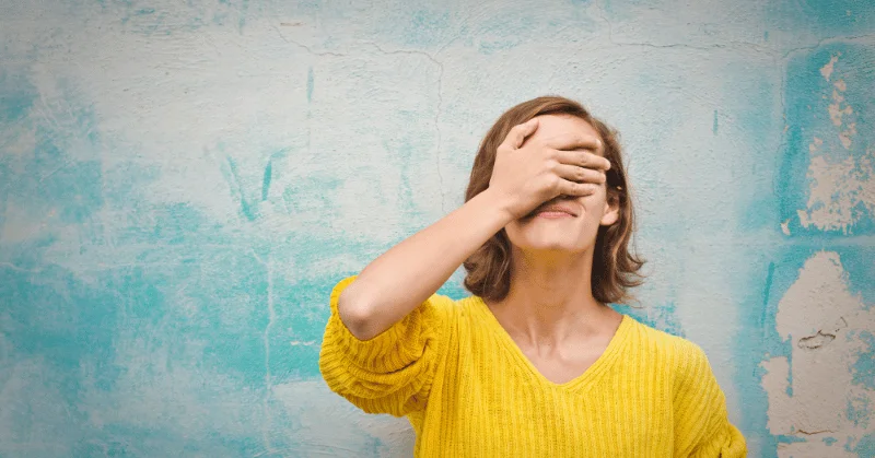 Woman covering her face with her hand, regretting her choices and dwelling on the past, demonstrating wasting time