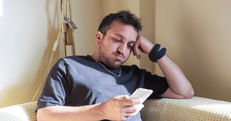 Man looking at his smartphone, displaying the concept of time wasting activities