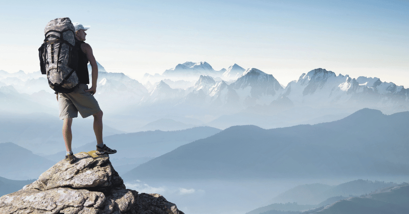 Man on the peak of mountains, demonstrating the concept of resilience throughout ups and downs in life