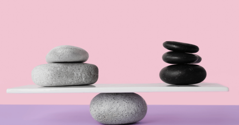 Stones on teeterboard, depicting finding the right balance when putting pressure on yourself