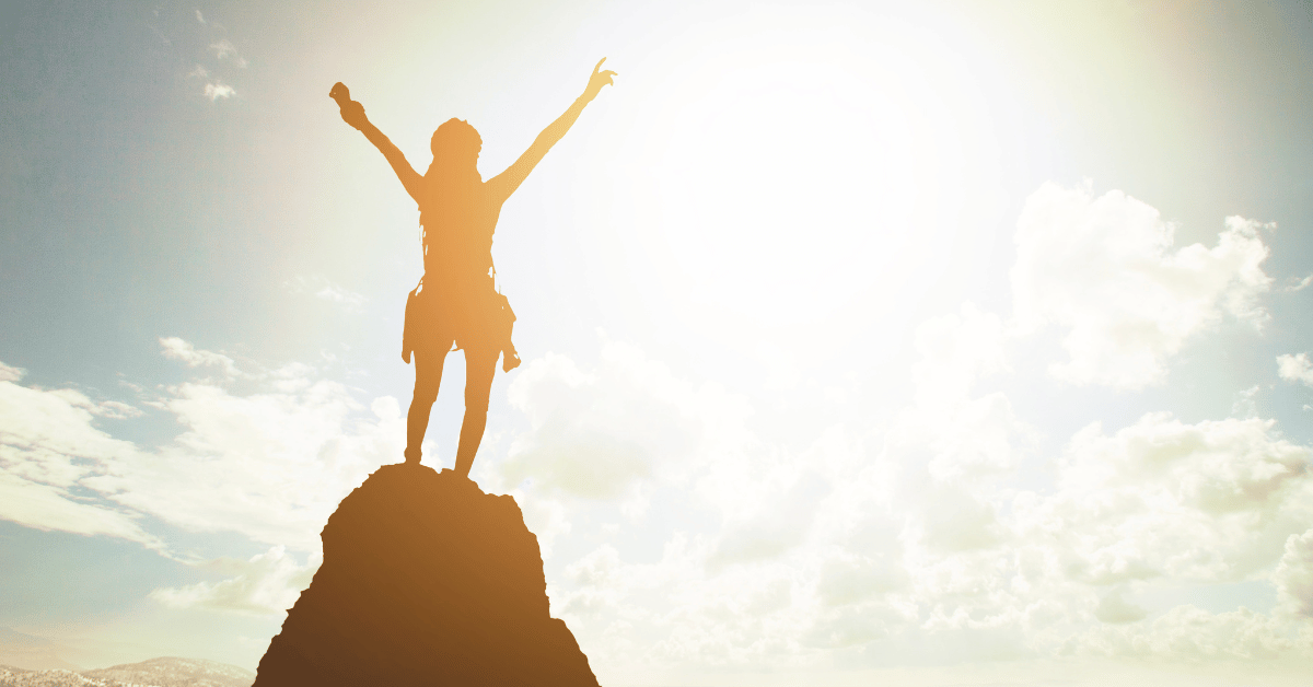 Woman on the top of the mountain symbolising traits of successful people