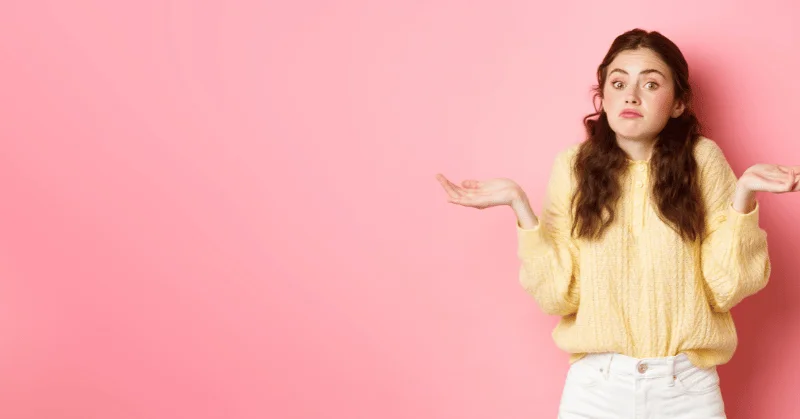 Woman shrugging her shoulders clueless due to indecision, symbolising wasting time 